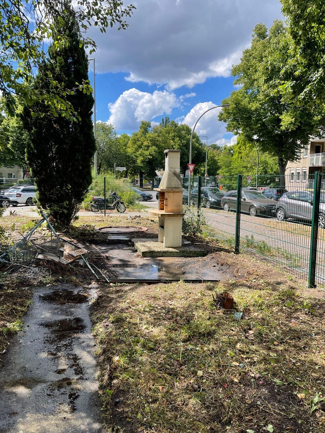 Freigelegter Grillplatz mit gemauertem Kamin nach der Grünreinigung an einer Berliner Straße