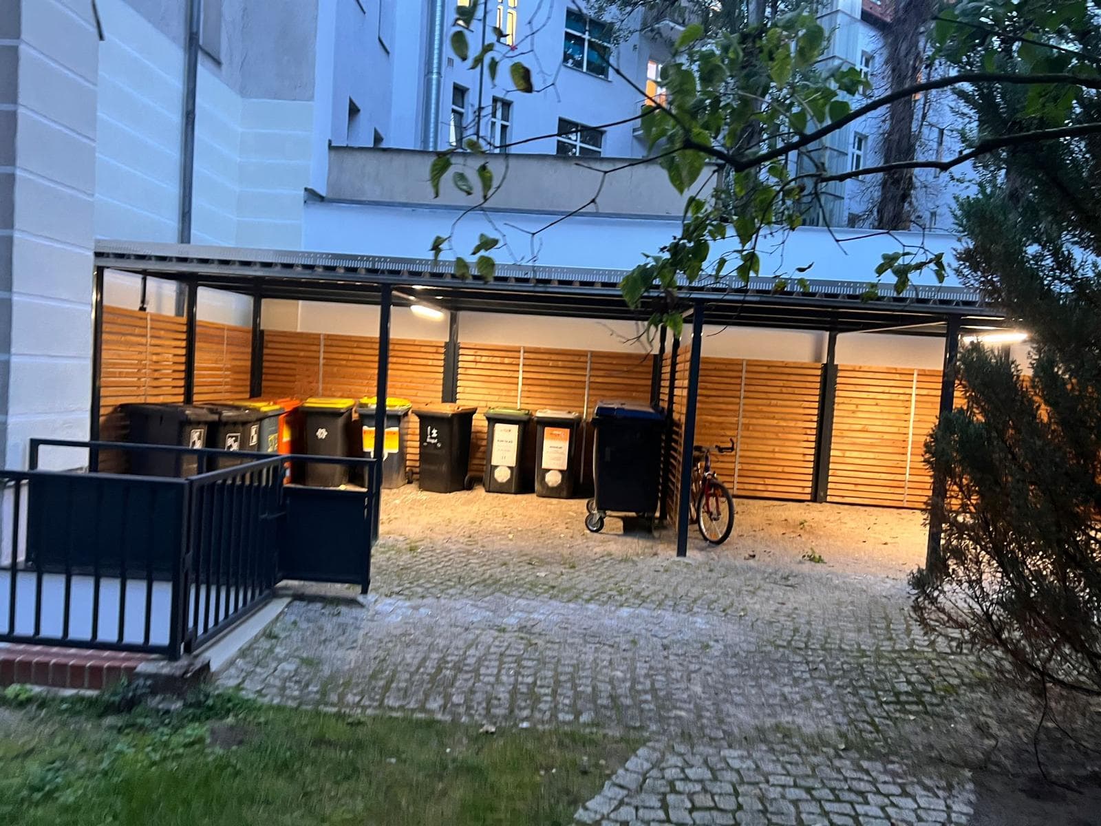 Neu gebaute Stahlüberdachung mit Holzverkleidung und Beleuchtung über einem Mülltonnenplatz in Berlin